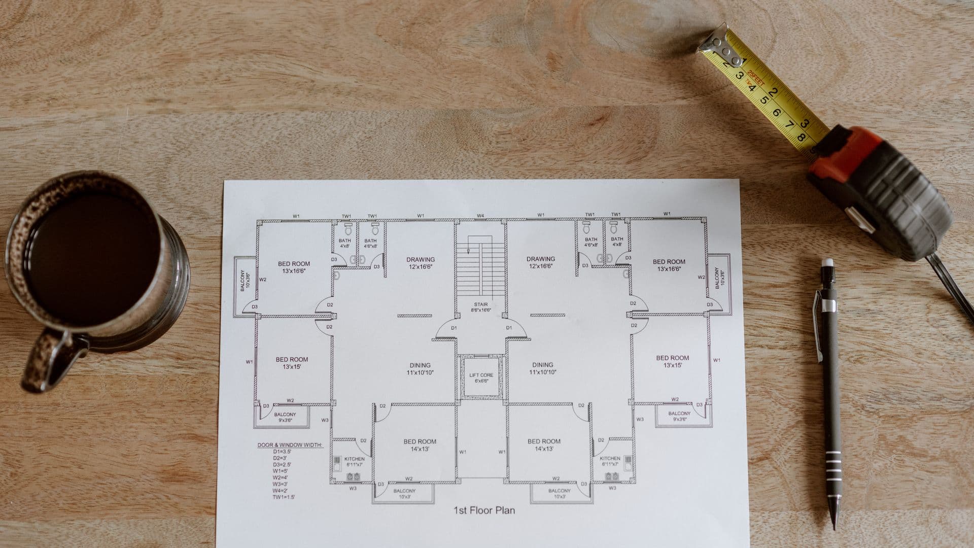 A room plan on a desk with a tape measure and a pen