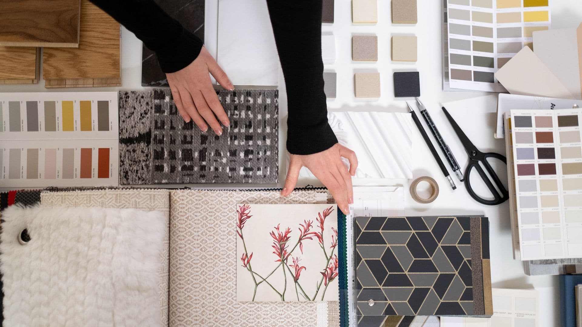 Hands laying out laminate and fabric samples on a table