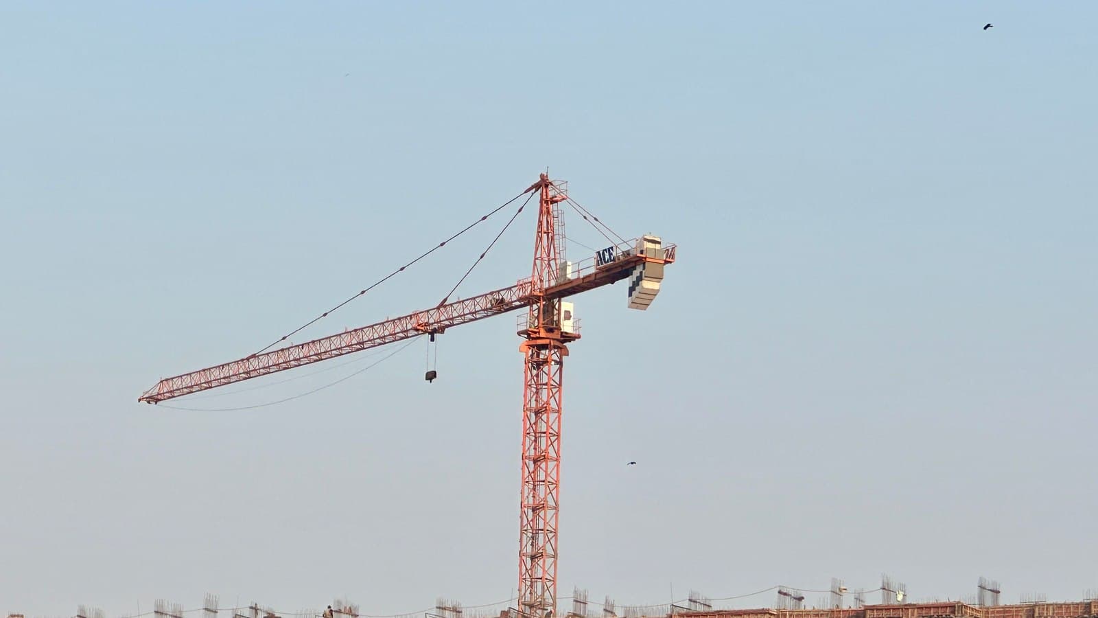 A red tower crane at a building site in Mumbai against a clear sky