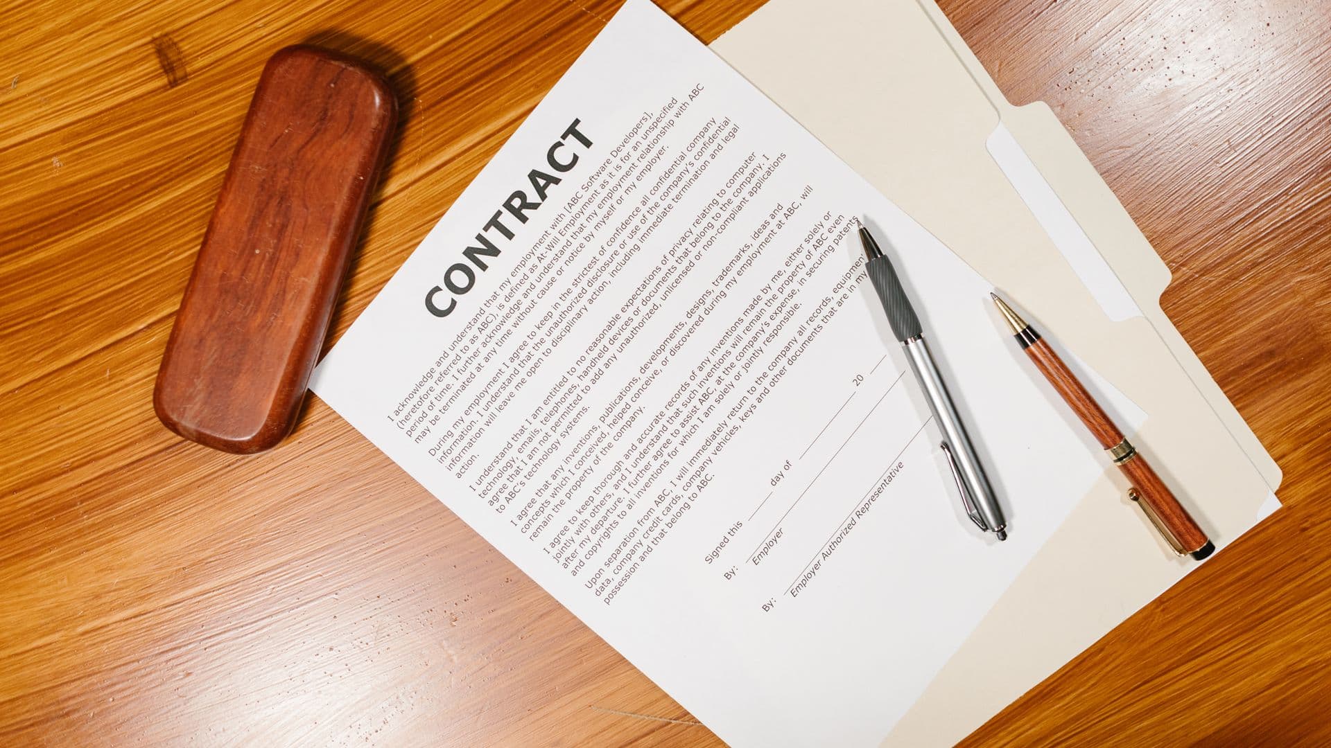 A contract lying open on a desk with two pens beside it