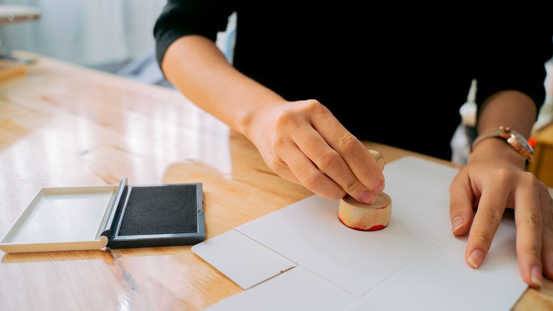 A hand pressing a rubber stamp onto a sheet of paper