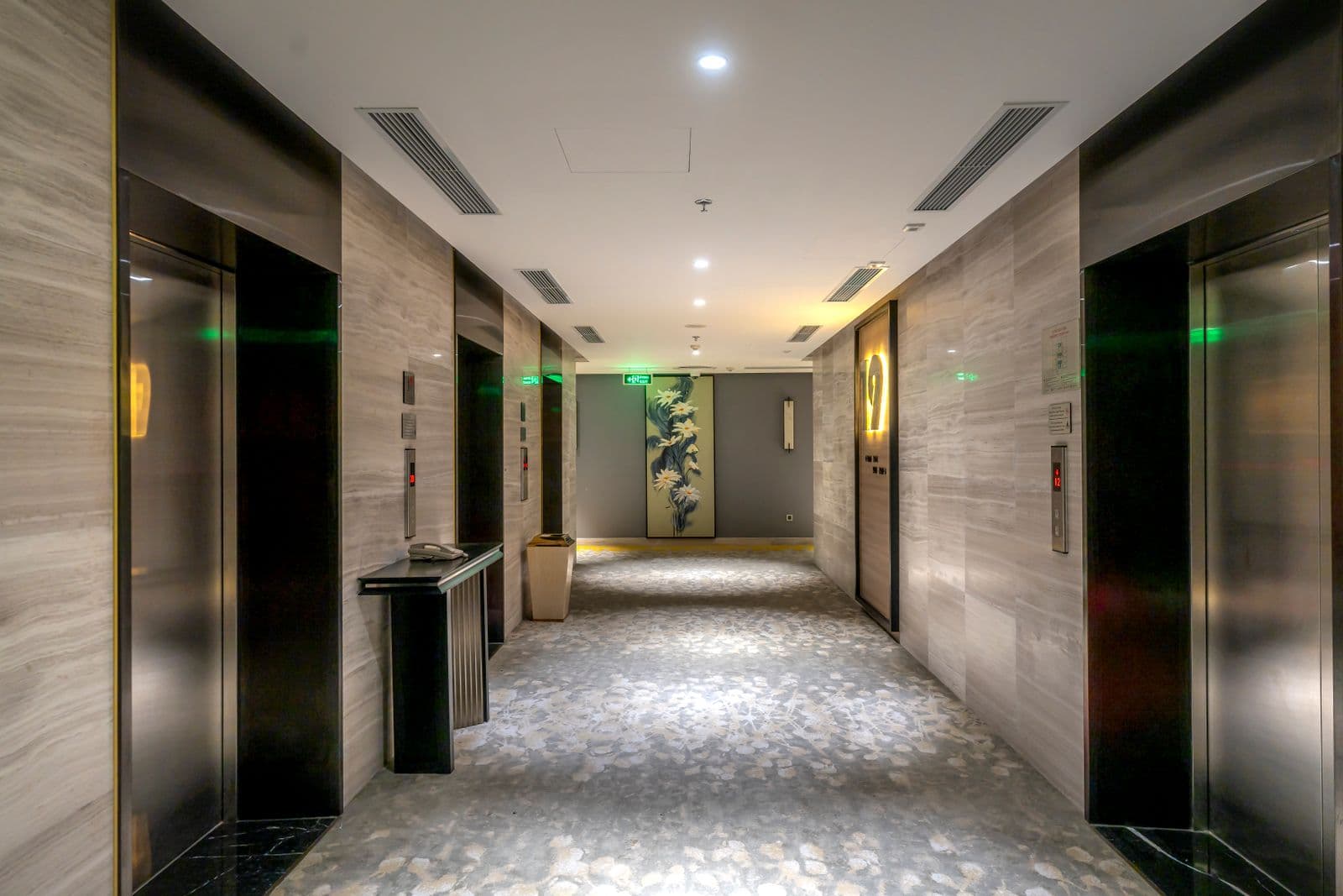 A quiet lift lobby finished in stone and brass