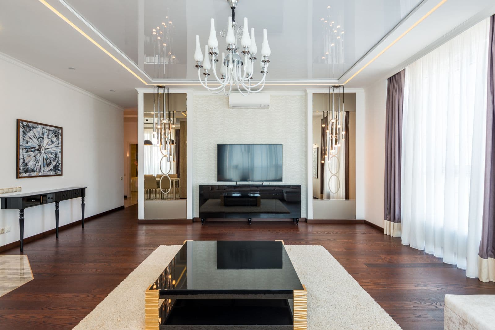 A formal living room with a chandelier and dark wood floor