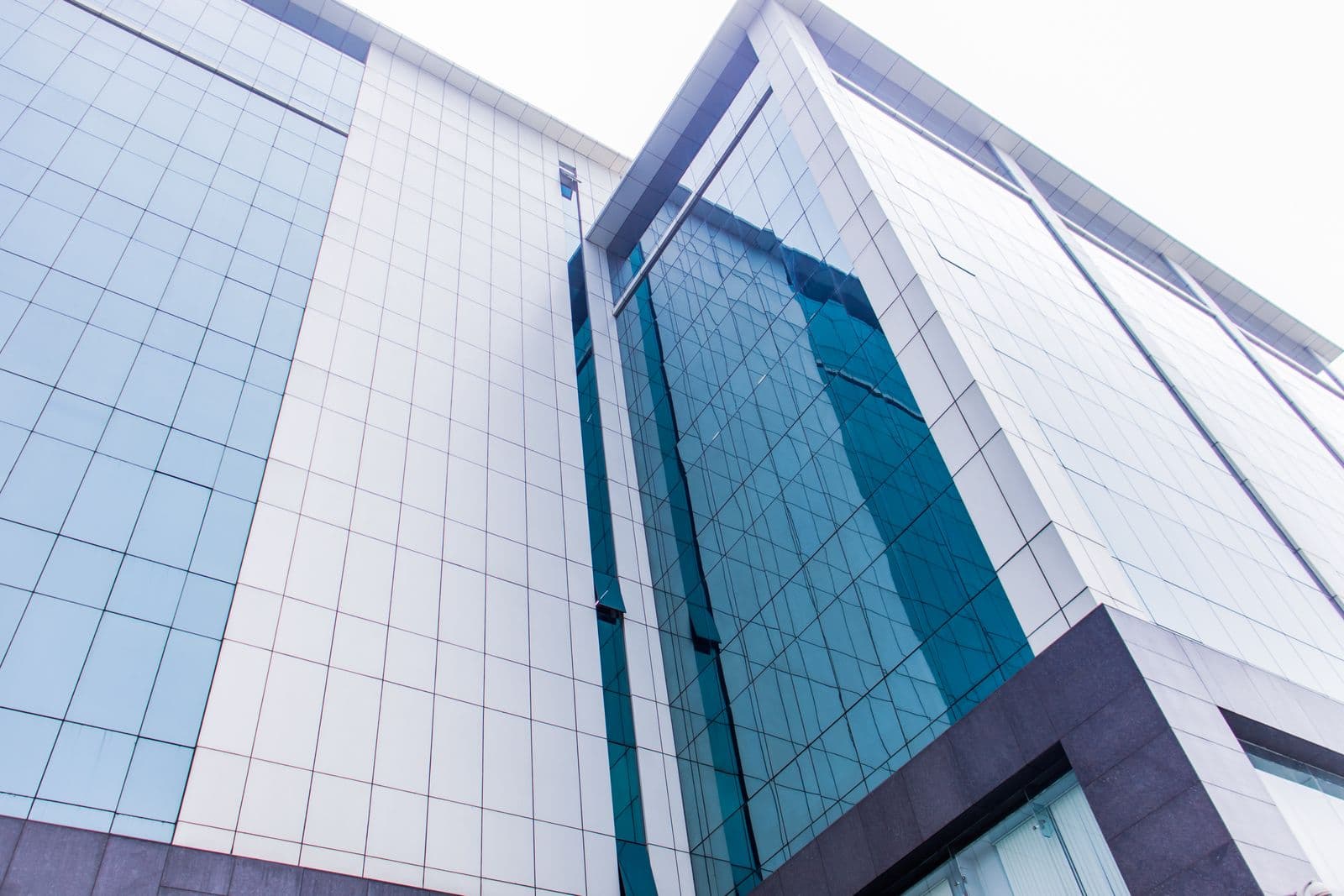 The glass facade of an office tower seen from below