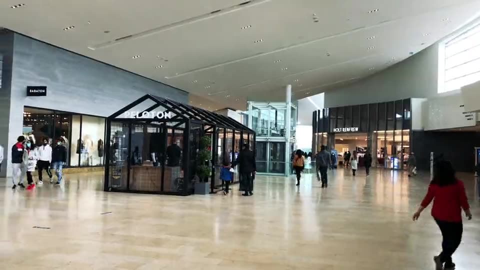 Shoppers walking a covered shopping arcade lined with glass shopfronts